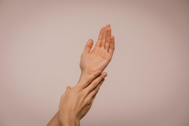 A person touching their hand on a pink background