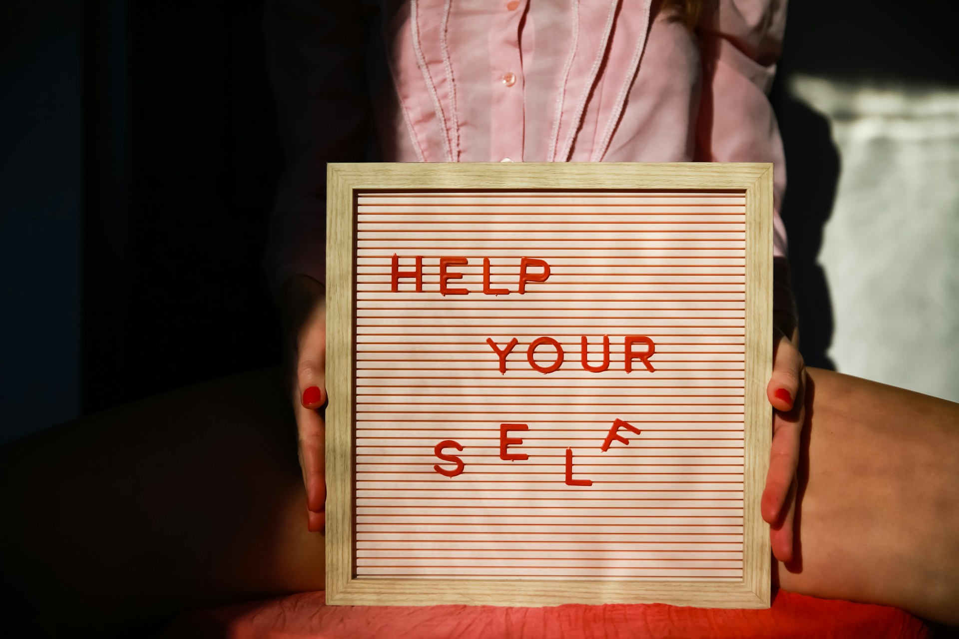 A person holding a frame containing the words: HELP YOURSELF; choosing not to self-sabotage
