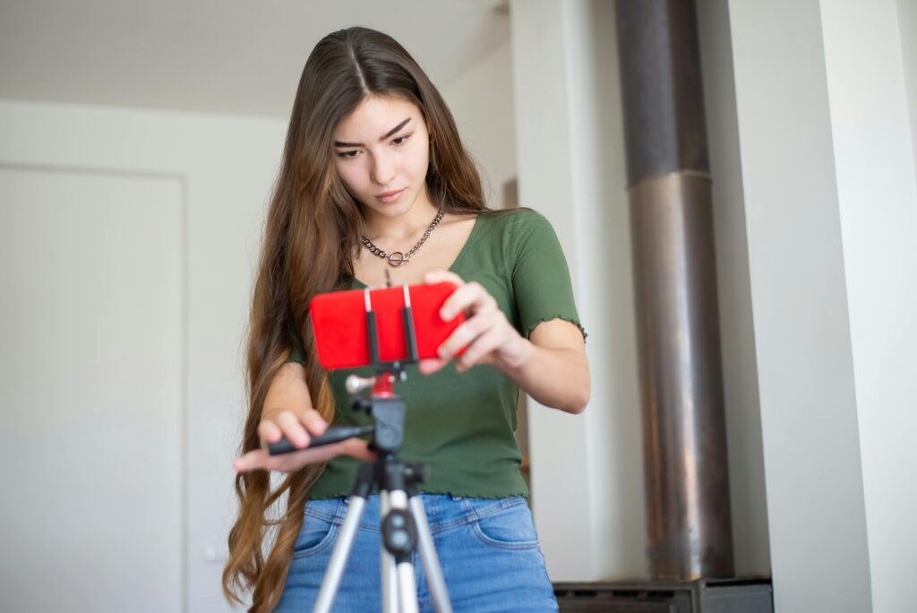 woman adjusting red phone on tripod 