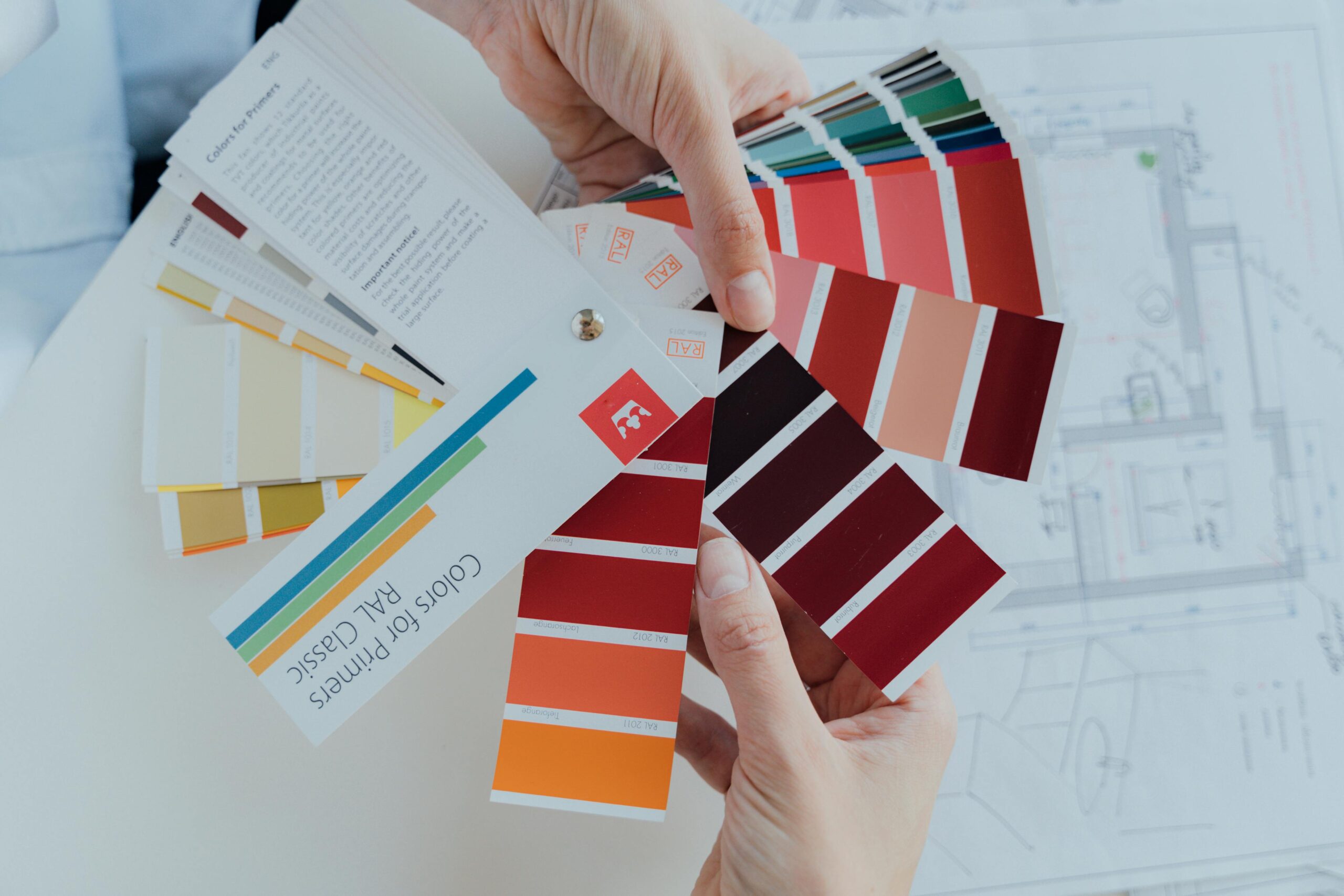 person holding several paint chip colors of red and similar colors