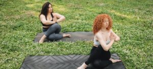 two women practising yoga in a park